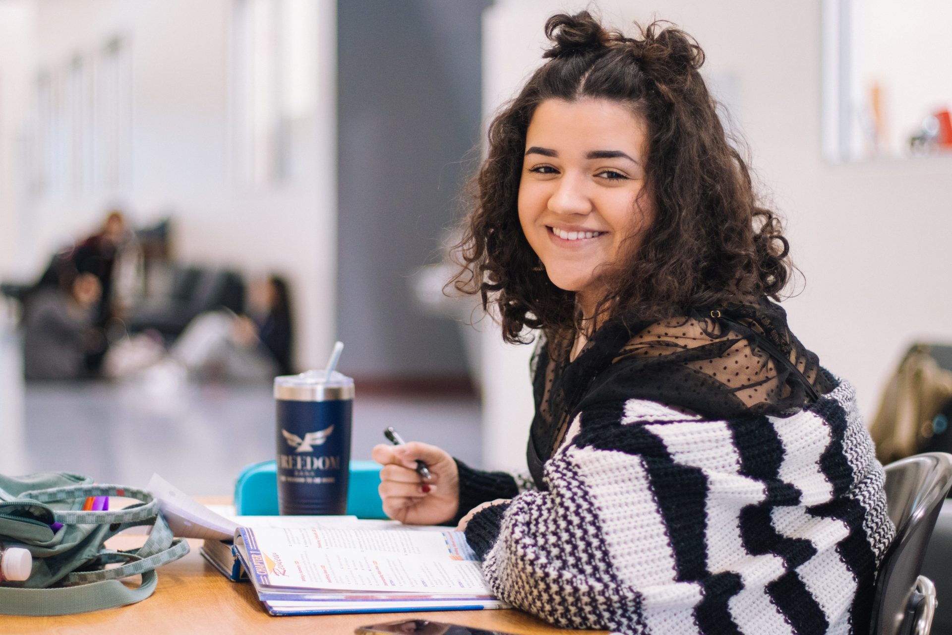 studentessa studia su un libro aperto e sorride alla camera